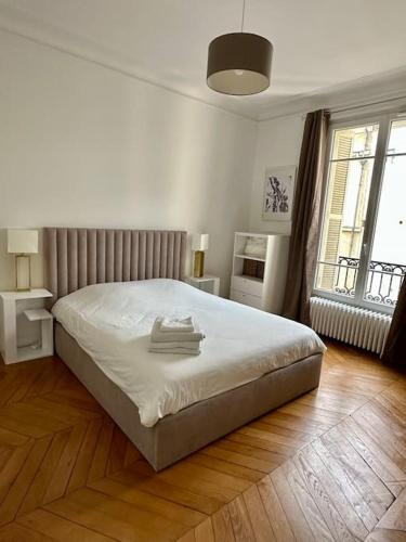 Cette chambre comprend un lit avec des draps blancs et du parquet. dans l'établissement Splendide Appartement au coeur de St Germain / Odéon, à Paris