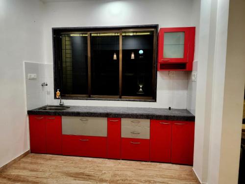 une cuisine rouge avec un évier et une fenêtre dans l'établissement ReUnion Villa ll Swimming Pool ll Snooker ll AC ll BBQ ll 3BHK, à Lonavala