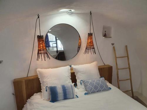 a bedroom with a mirror and a bed with pillows at L'Exquishette de Lourmarin, un nid sur les toits. in Lourmarin