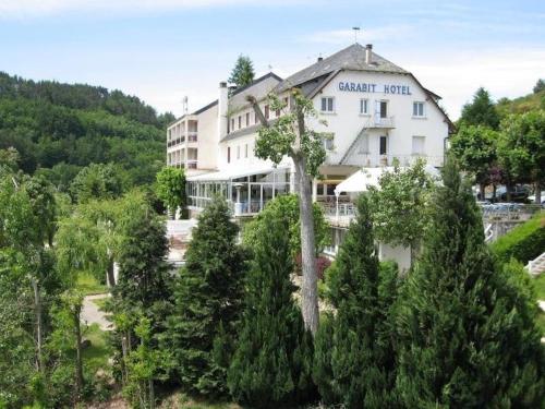 a large white building in the middle of trees at Garabit Hotel in Garabit