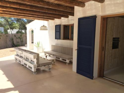 a porch with a bench and a blue door at A beautiful villa close to the beach in Playa Migjorn