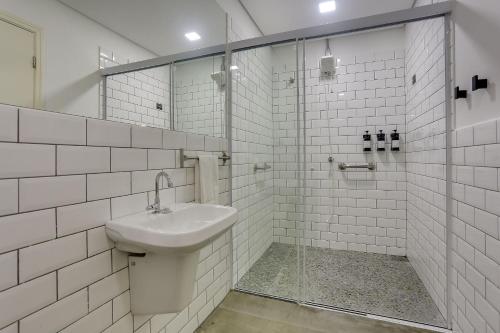 een witte badkamer met een wastafel en een douche bij Hotel 1948 in Holambra