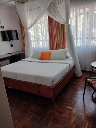 een slaapkamer met een bed met een oranje kussen erop bij Annodas Homes Milimani Kisumu in Kisumu