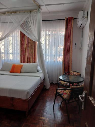 een slaapkamer met een bed, een tafel en een raam bij Annodas Homes Milimani Kisumu in Kisumu