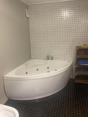 a white tub in a bathroom with a tiled wall at Spacious apartment in beautiful Norway countryside close to trondheim fjord 