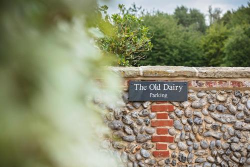 a sign on a brick wall that reads the old dairy parking at The Old Dairy in Holt