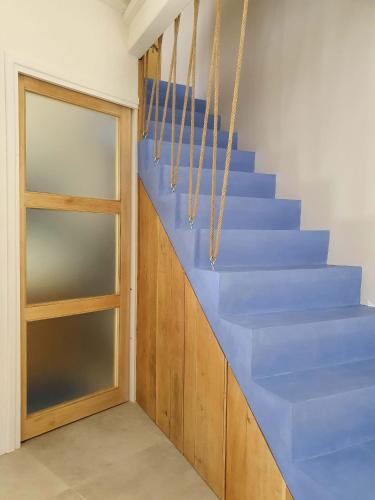 a stairwell with blue stairs and a door at L'Exquishette de Lourmarin, un nid sur les toits. in Lourmarin