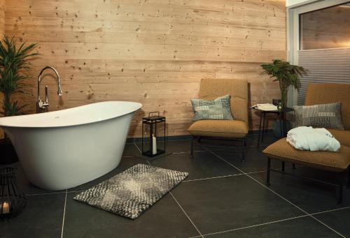 a bathroom with a tub and two chairs and a table at VÜ Terrassen-Chalets in Münchberg