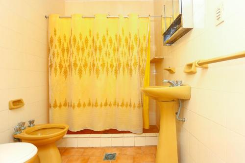 a bathroom with a yellow shower curtain and a toilet at Amplia Quinta Familiar en Sauce Viejo in Sauce Viejo