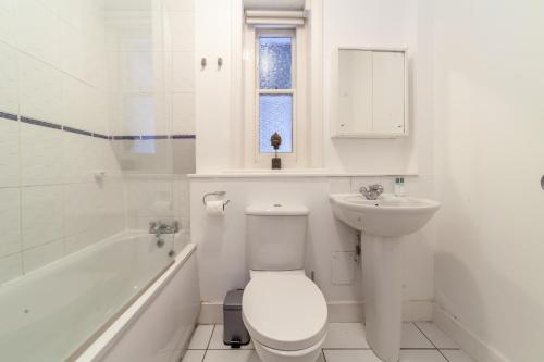 a white bathroom with a toilet and a sink at The Maida Vale Flat in London