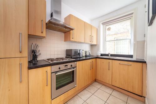 a kitchen with wooden cabinets and a stove top oven at The Maida Vale Flat in London