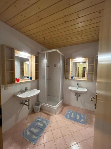 a bathroom with two sinks and a shower and two mirrors at Appartement Riepler in Wagrain