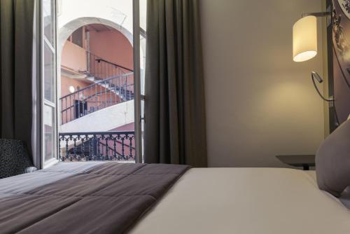a bedroom with a bed and a window with a staircase at Mercure Lyon Centre Beaux-Arts in Lyon