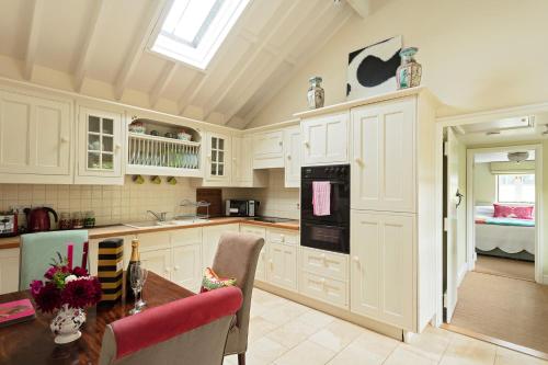 a kitchen with white cabinets and a table with flowers on it at The Old Dairy in Holt