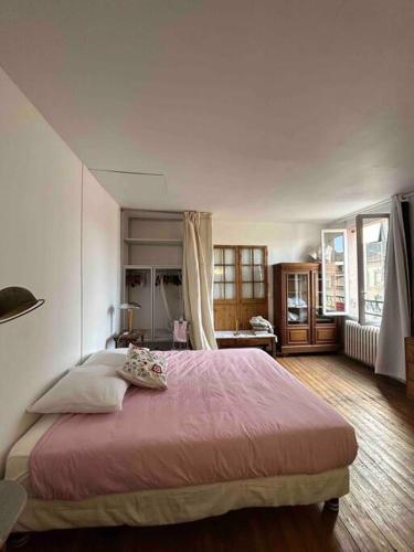une chambre avec un grand lit avec une couverture rose dans l'établissement Maison 50m2 proche Paris pour 2, à Pantin