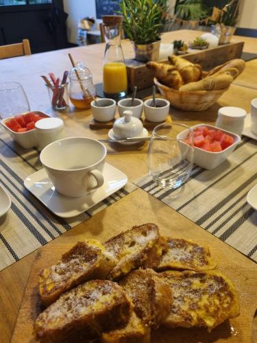 a table with a plate of bread and bowls of fruit at ATELIER 19 Maison d'Hôtes in Varesnes