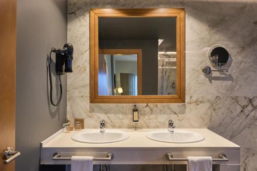 a bathroom with two sinks and a mirror at Hotel Versatile in Guarda