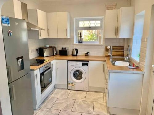 a kitchen with white cabinets and a washer and dryer at 3 Bed Residential home - 5 mins from M4 in Port Talbot