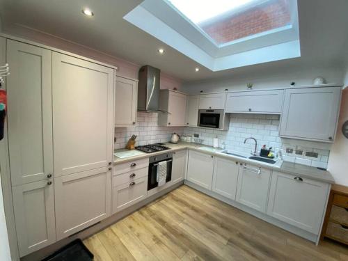 a large kitchen with white cabinets and a skylight at Hot Tub, King Bed, Central, Modern Beach House in Cleethorpes