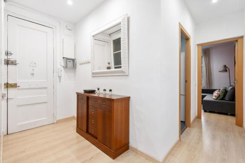 RECENTLY RENOVATED 2 BEDROOM APARTMENT IN EIXAMPLE في برشلونة: غرفة بيضاء مع خزانة خشبية ونافذة