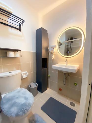 a bathroom with a toilet and a sink and a mirror at Serene Skyline Escape Las Pinas in Manila
