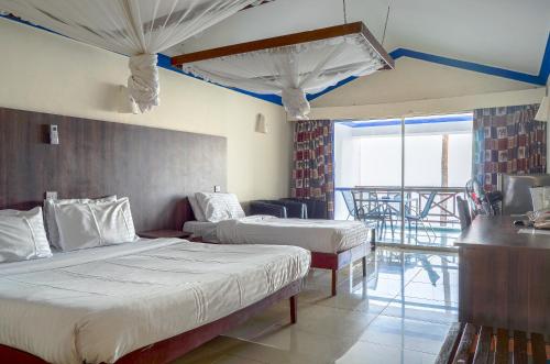 um quarto de hotel com duas camas e uma varanda em Sai Rock Beach Hotel & Spa em Bamburi