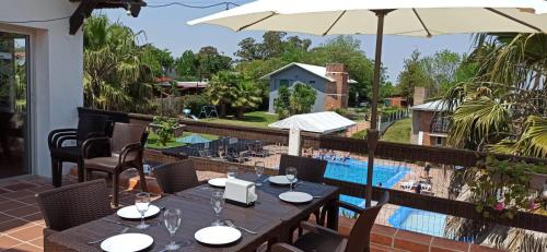 une terrasse avec une table et un parasol ainsi qu'une piscine dans l'établissement Posada de Britopolis, à Colonia Valdense