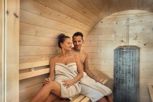 a man and woman sitting in a sauna at VÜ Terrassen-Chalets in Münchberg