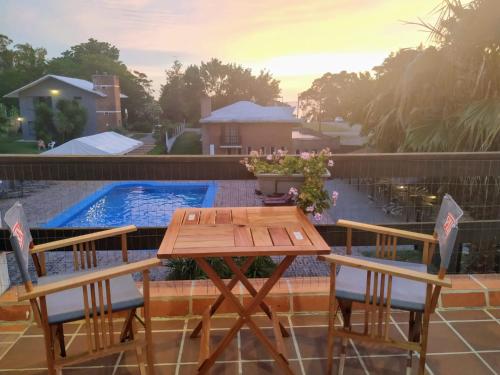 - une table et des chaises en bois à côté de la piscine dans l'établissement Posada de Britopolis, à Colonia Valdense