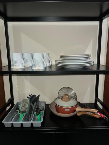 a shelf with a pot and utensils and dishes at Apartement Vida View, 2BR comfy place by Als in Pampang