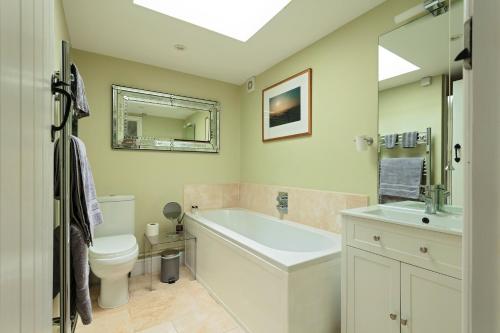 een badkamer met een bad, een toilet en een wastafel bij The Old Dairy in Holt