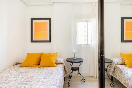 1 Schlafzimmer mit 2 Betten, gelben Kissen und einem Tisch in der Unterkunft Apartamento amplio con 4 habitaciones y 2 baños - Great apartment with 4 rooms - 2 baths in Sevilla