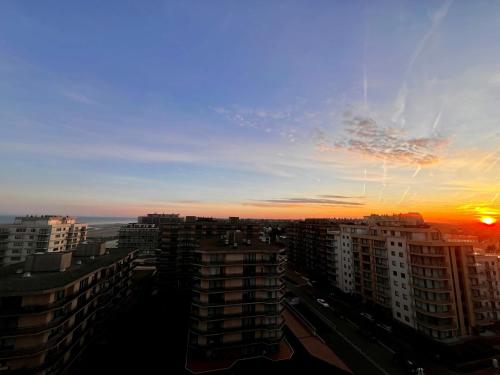 a sunset over a city with tall buildings at Appartement Sainte-Cécile in De Panne