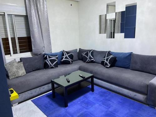 a living room with a gray couch with pillows at Apparemment TAMARIS in Dar Bouazza