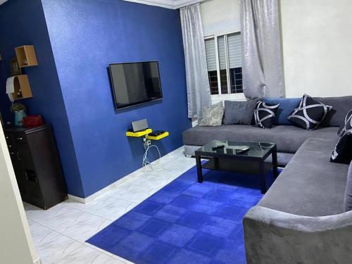 - un salon bleu avec un canapé et une télévision dans l'établissement Apparemment TAMARIS, à Dar Bouazza
