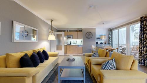 uma sala de estar com um sofá amarelo e uma mesa em Apartmenthaus Binzer Sterne em Binz