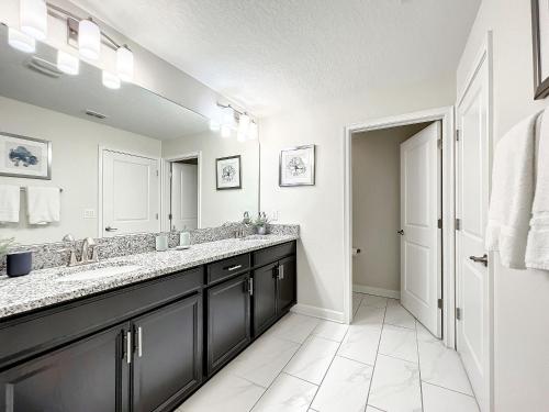 La salle de bains est pourvue de 2 lavabos et d'un grand miroir. dans l'établissement Stunning 5 bedroom house near Disney, à Davenport