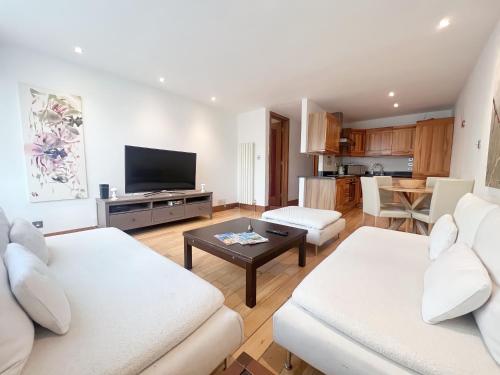 a living room with two white couches and a tv at Kensington Apartments in London