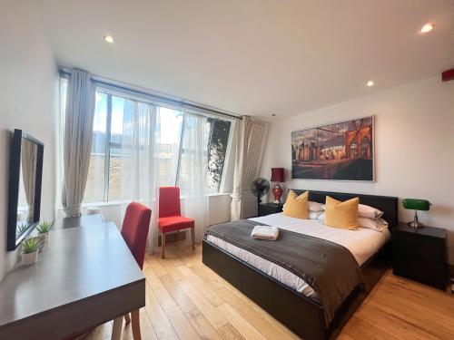 a bedroom with a bed and a table and a desk at Kensington Apartments in London