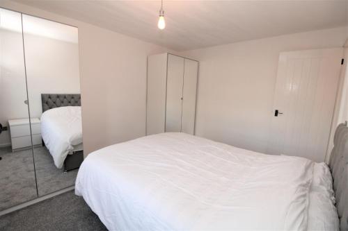 a bedroom with a white bed and a mirror at Lovely Flat Near Lewisham in Hither Green