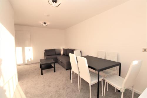 a dining room with a black table and white chairs at Lovely Flat Near Lewisham in Hither Green