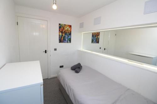 Habitación blanca con 2 camas y espejo. en Lovely Flat Near Lewisham, en Hither Green