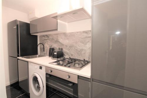 a small kitchen with a stove and a sink at Lovely Flat Near Lewisham in Hither Green
