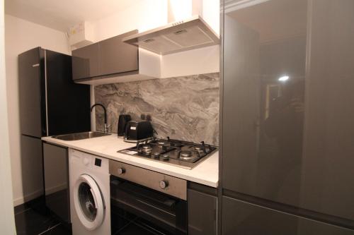 a kitchen with a stove and a washing machine at Lovely Flat Near Lewisham in Hither Green