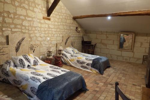 a bedroom with two beds and a brick wall at Chez Florence et Sylvain de Loudun in Loudun