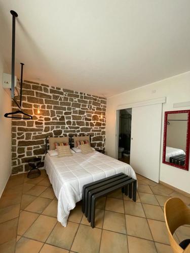 ein Schlafzimmer mit einem Bett mit Ziegelwand in der Unterkunft Excellent Rooms Paola's in Olbia