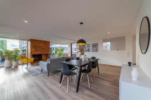 a dining room and living room with a table and chairs at Penthouse Chicalá Colombian Experience in Parque Virrey in Bogotá