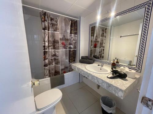 een badkamer met een wastafel, een toilet en een spiegel bij Piso de una habitación en Torremolinos in Torremolinos