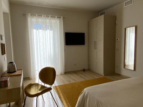 una camera con letto, sedia e televisore di Alba Room 16 ad Alba