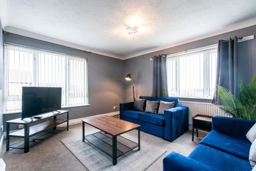 een woonkamer met een blauwe bank en een tv bij 3 Bed Apartment - Perfect for Contractors near Liverpool Airport in Hale